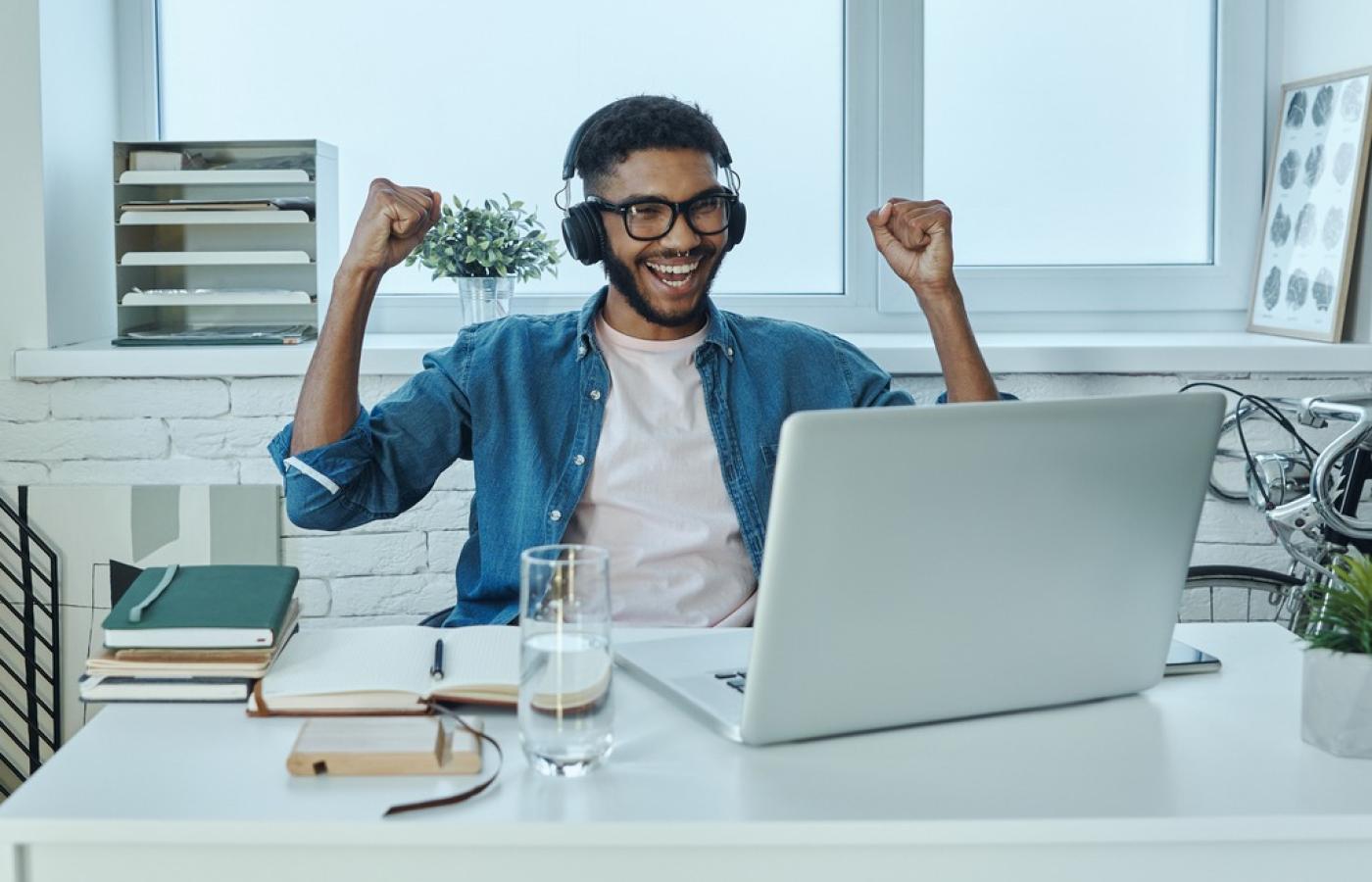 Programmer at their desk with hands raised in excitement