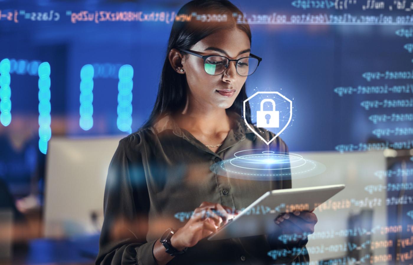 A women looks at a tablet and an image of a lock hovers above representing cybersecurity.